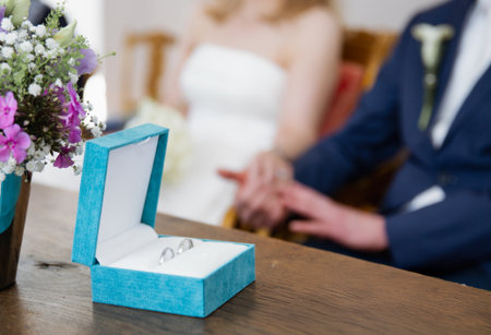 Close up of a blue box with two silver wedding rings on a wooden table, blurred backgroundの写真素材