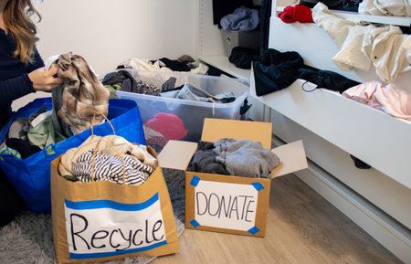 Close up of a young woman sorting clothes from her wardrobe for recycling and donation
