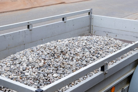 Trailer filled with small gravel stones parked on a construction site, showing a close-up view of...