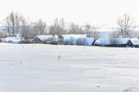 Snow-covered village near the field in winterの写真素材
