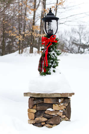 Lamp post with green and red Christmas decorations and snowの写真素材