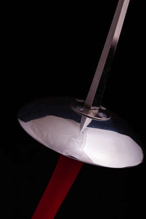 closeup of a foil sword with a red handle and black background