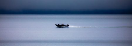 Two people in a fishing boat driving on Chequamegon Bay, on Lake Superior off of Washburn, Wisconsin in September, panoramaの写真素材