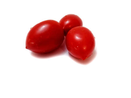 On a white background, three red tomatoes with water droplets.の写真素材