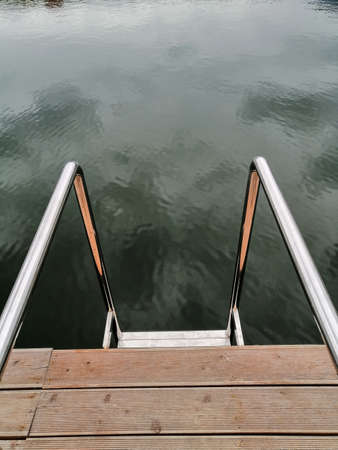 Natural backdrop of a decorative lake with a small wooden platform with iron handrails.の写真素材