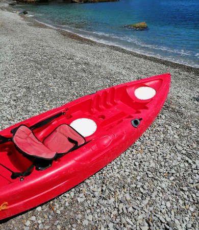 Against the background of the sea shore and the incoming wave, the kayak is red.の写真素材