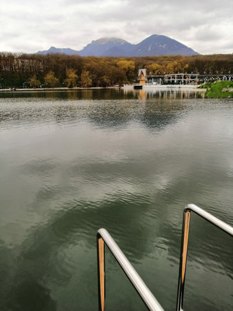 The quiet,calm sueface of the river, a bridge in the form of a descent against the background of blue mountains.の写真素材