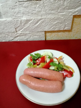 Sausages with salad on a white plate on a red backgroundの写真素材