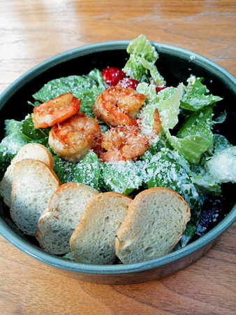Caesar salad with prawns and croutons on wooden tableの写真素材