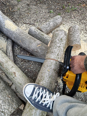 man sawing a log with a chainsaw, close-upの写真素材