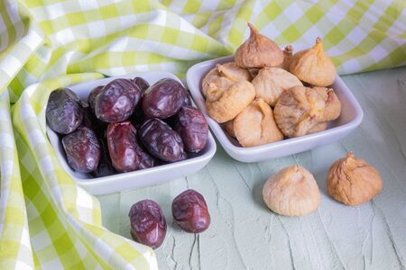 Dates and figs are on the table. Near the green tablecloth.