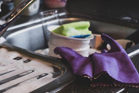 iron sink with dirty dishes and gloves in the kitchenの写真素材