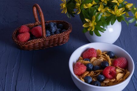 berries in a basket and granola on a table on a blue background