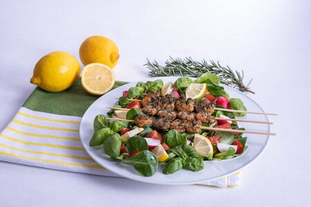 shrimp dinner on sticks and vegetables in a white plate on a table on a white backgroundの写真素材