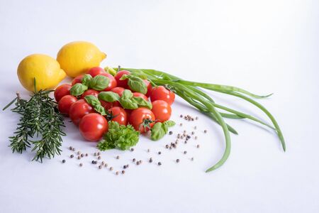 vegetables, green onions, lemons, basil and fresh tomatoes on the table on a white backgroundの写真素材