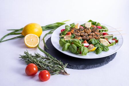 various vegetables and a plate of shrimp on sticks stands on a black tray on the table on a white backgroundの写真素材