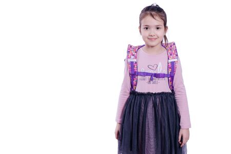 schoolgirl with a school bag on his back on a gray background