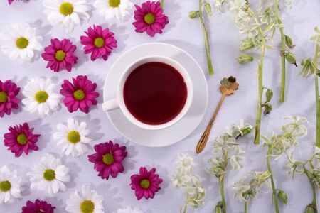 cup of coffee and buds of chrysanthemums on a white plate on a tableの写真素材