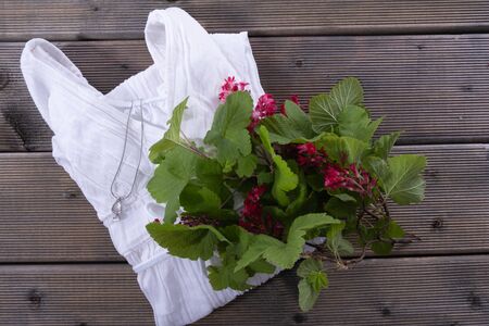 currant leaves and flowers lie on a white blouse on a wooden table