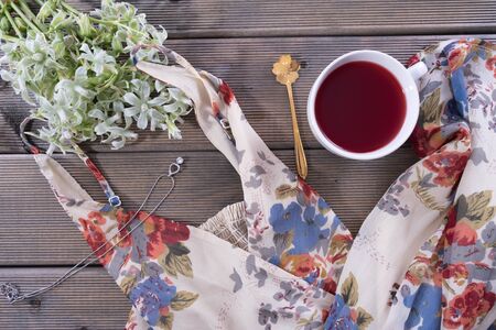 on the table is a cup of coffee, next to a women's dress on a wooden tableの写真素材
