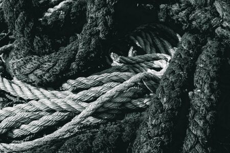 black and white photo old nautical ropes and ropes stacked in a large pile at the port