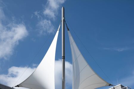 white sails with a mast over a building on a blue sky in spring