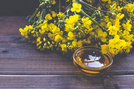 bouquet of blooming rapeseed and oil on a wooden table on in the morning lightの写真素材