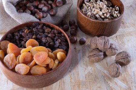 various dried fruits, apricot, nuts and raisins in a wooden cup on a wooden backgroundの写真素材