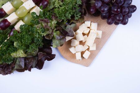 pieces of cheese, grapes with lettuce on a table on a white backgroundの写真素材