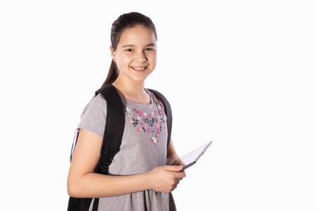 schoolgirl smiles, holds a tablet in her hands and looks away on a white background