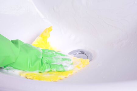 gloved hand cleans the sink in the bathroom on a white backgroundの写真素材