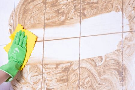 woman washes a dirty wall in a bathroom on a white backgroundの写真素材
