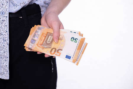 holding a small stack of euro banknotes, on a white backgroundの写真素材