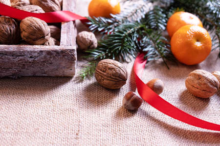 christmas delicacy tangerines and nuts, red ribbon and spruce branchesの写真素材