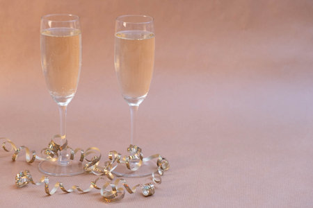 Champagne glasses entwined with ribbon stand on the New Year's table on a beige backgroundの写真素材