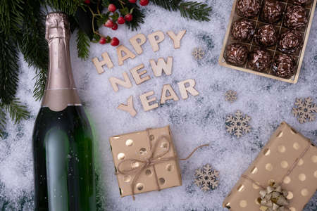 a bottle of champagne and gifts, and the snow says "Happy New Year" on a white backgroundの写真素材