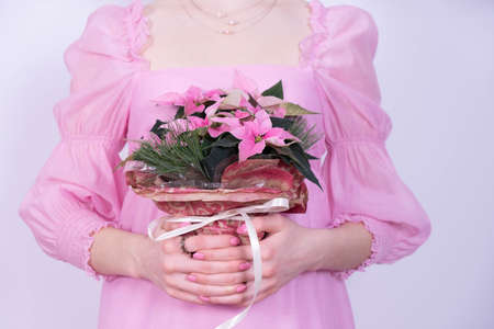 young girl in a pink dress holding a bouquet of christmas flowers on a white backgroundの写真素材