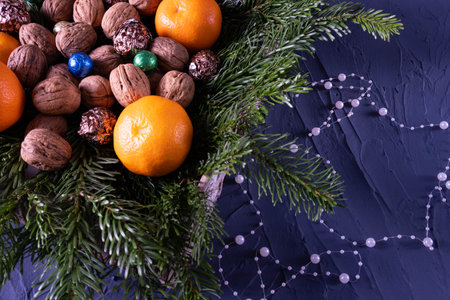 Tangerines, sweets and nuts on the table on fir branches, on a blue backgroundの写真素材