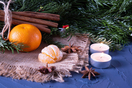 Candles are burning, tangerines on burlap, fir branches on the table, on a blue backgroundの写真素材