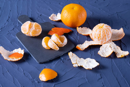 Whole and peeled juicy tangerines on the table, on a blue backgroundの写真素材