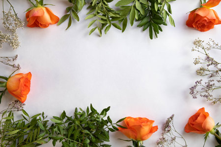 orange roses and decorations on different sides of a white background, top viewの写真素材