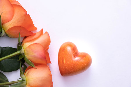 three orange roses and a stone heart on a white background, top viewの写真素材