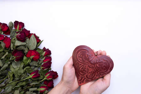 large bouquet of red, dried roses on a white background and hands holding a red heart, top viewの写真素材