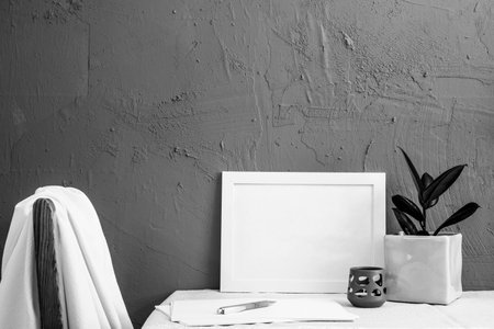 chair back, white photo frame, candlesticks, house plant on a gray background on the table