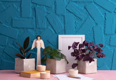 home plants, antique book, writing materials, burning candles, wooden angel figure and photo frame...