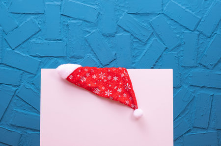 Christmas cap hanging on a white background, on a blue background