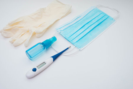 thermometer, face mask, gloves and antiseptic on a white background on the table