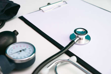note sheet, stethoscope and pressure meter on white background on tableの写真素材