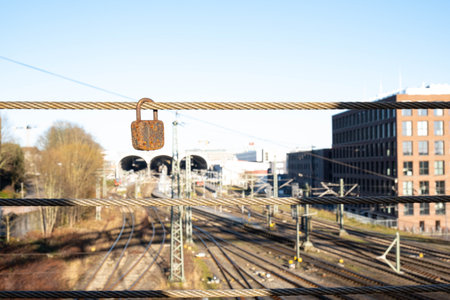rusty lock hangs on the iron cable of the bridge, above the railway, on the streetの写真素材
