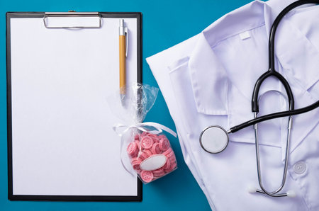 stethoscope, sweets, notepad, pen, folded form of a doctor lie on the table, on a blue backgroundの写真素材